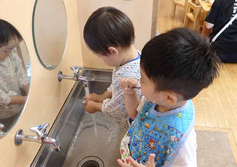 スプーンを洗う子の横には、すでに終わって歯を磨く子が